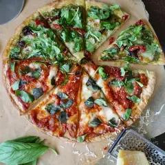 Dwie połówki pizzy: jedna z pesto i rukolą, druga z sosem pomidorowym i bazylią. Zastanawiasz się, ile kosztuje pizza w Czechach?