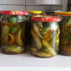 Słoiki z ogórkami krokodylkami z chili i czosnkiem, gotowe do spiżarni.