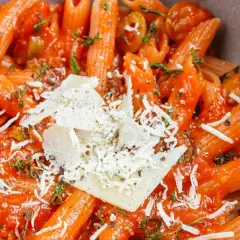 Szybki obiad z makaronem penne w sosie pomidorowym, posypany parmezanem i ziołami. Idealne danie na szybki posiłek.