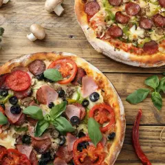 Dwie pizze z różnymi dodatkami: jedna z salami, papryką i pieczarkami, druga z szynką, pomidorami i oliwkami. Idealne na wspólne jedzenie, pokazujące jakie dodatki do pizzy wybrać.