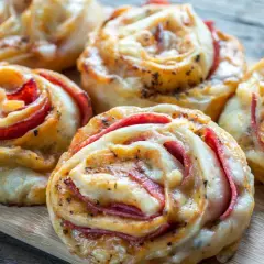 Pyszne roladki z ciasta do pizzy z serem i wędliną, idealne na przekąskę.