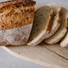 Chleb domowy, pokrojony na kromki, leżący na drewnianej desce.
