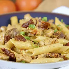 Penne z kurczakiem i suszonymi pomidorami, posypane szczypiorkiem. Pyszne danie, które zachwyci każdego smakosza.