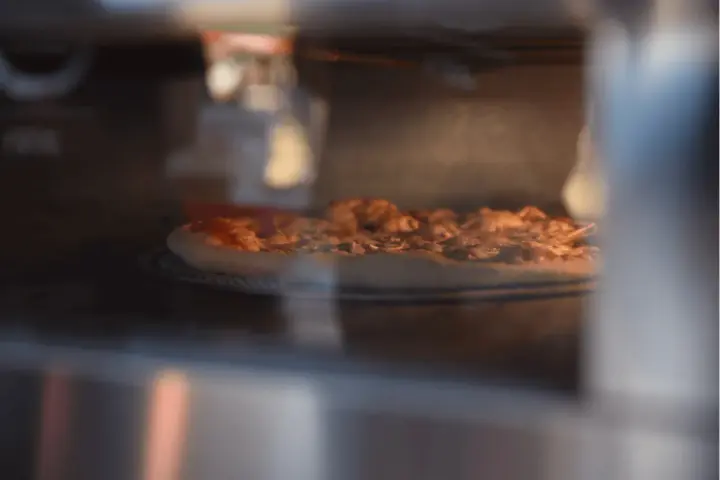 Pizza Dr. Oetker piecze się w piekarniku, apetycznie rumieniąc.