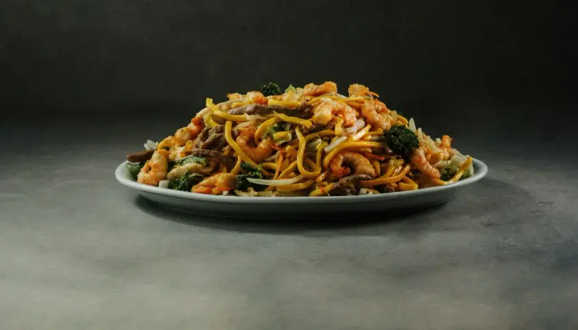 Talerz pełen aromatycznego, smażonego makaronu z krewetkami, wołowiną i brokułami.