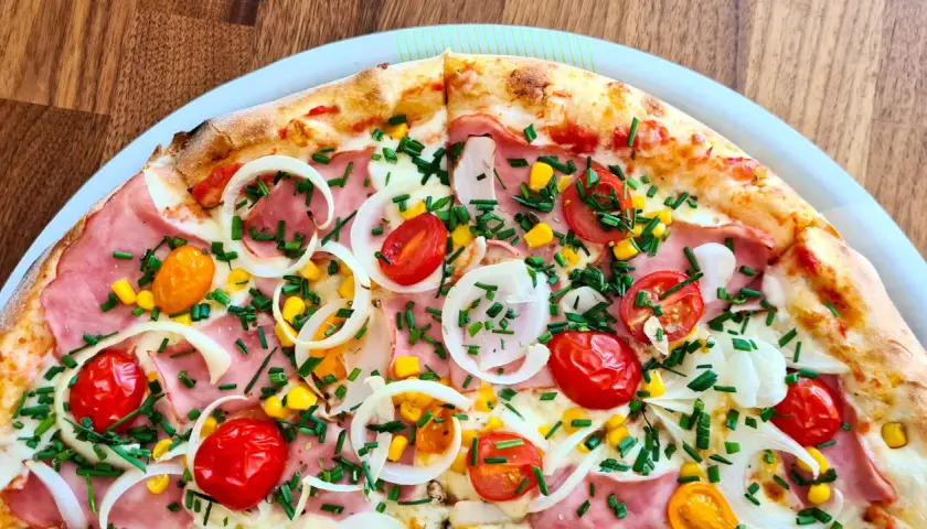 Pyszna pizza 32 cm na ile osób? Ta z szynką, pomidorkami, kukurydzą i cebulą z pewnością zadowoli 2-3 głodomorów.