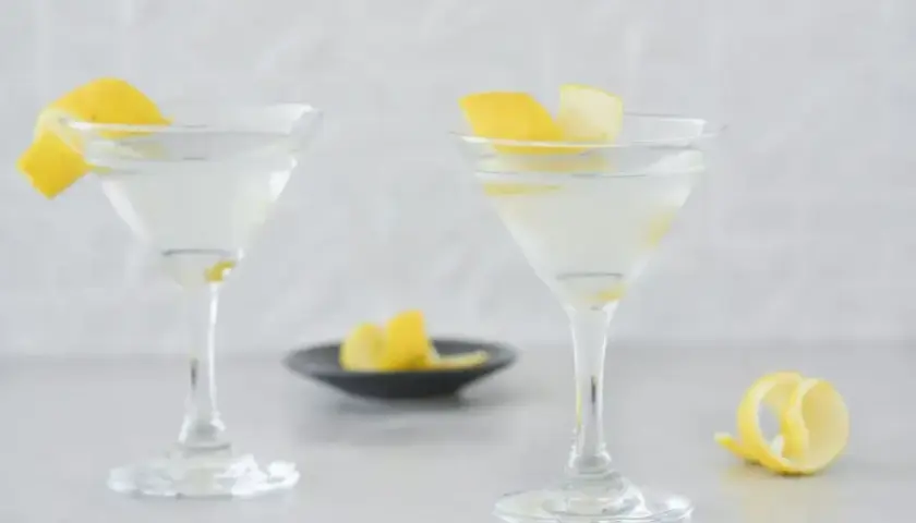 Dwa eleganckie drinki z martini, ozdobione skórką cytrynową, czekają na spróbowanie.