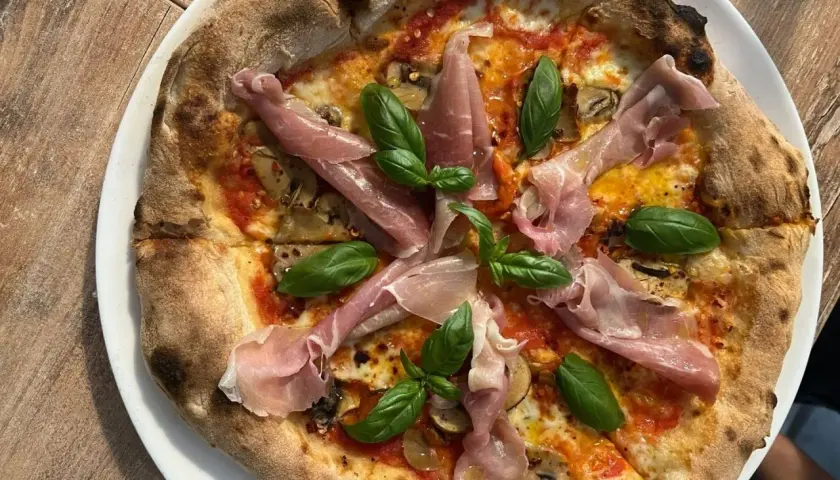 Pyszna pizza z szynką parmeńską i bazylią. Zastanawiasz się, ile kosztuje pizza w Chorwacji? Ta wygląda na wartą swojej ceny!