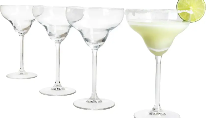Cztery kieliszki do margarity, jeden z zielonym drinkiem i plasterkiem limonki, pozostałe puste.