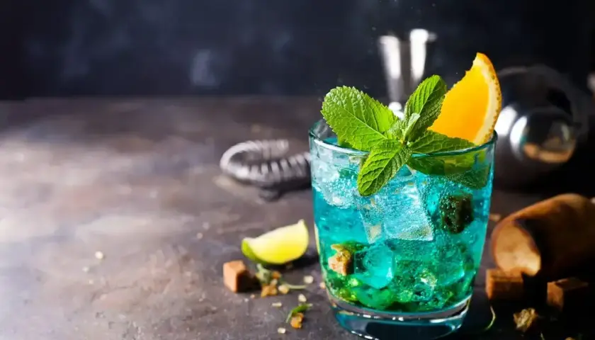 Orzeźwiający drink Blue Lagoon z miętą i pomarańczą, idealny na letnie wieczory.