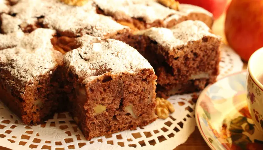 Wilgotne ciasto cynamonowe z jabłkami i orzechami, posypane cukrem pudrem. Idealne na jesienną herbatkę.