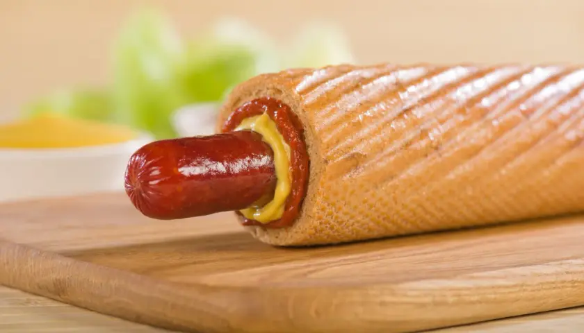 Pyszny hot dog francuski z musztardą i ketchupem na desce.