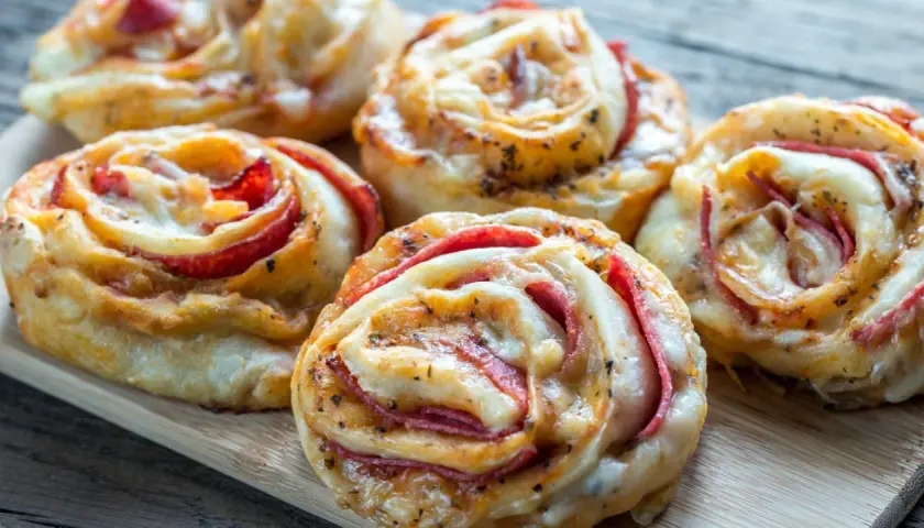 Pyszne roladki z ciasta do pizzy z serem i wędliną, idealne na przekąskę.