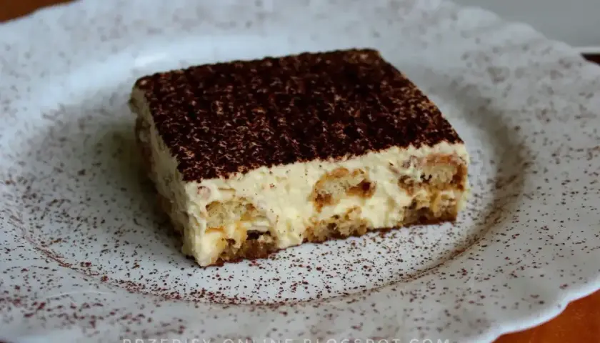 Pyszne tiramisu, czyli zabajone, na białym talerzu, posypane kakao. Idealne na deser.