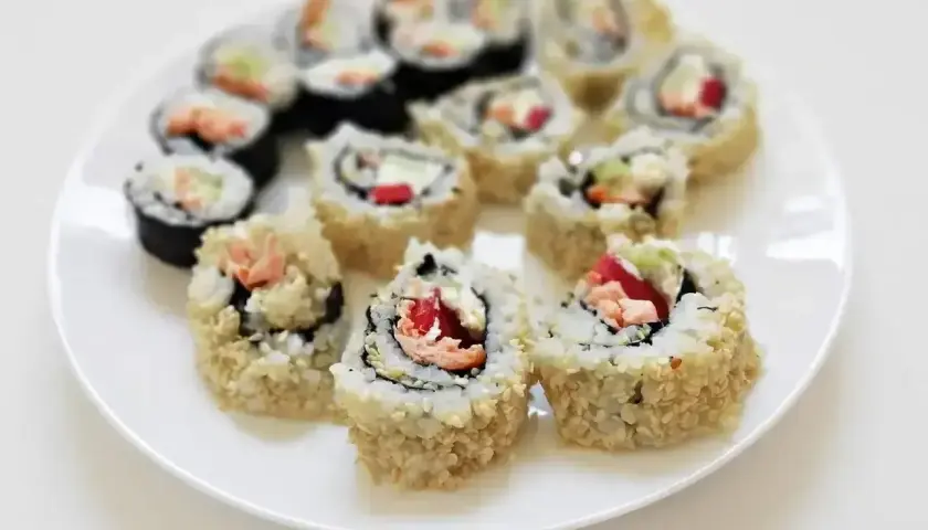 Talerz pełen california sushi, z łososiem, awokado i sezamem. Pyszne, domowe rolki sushi.