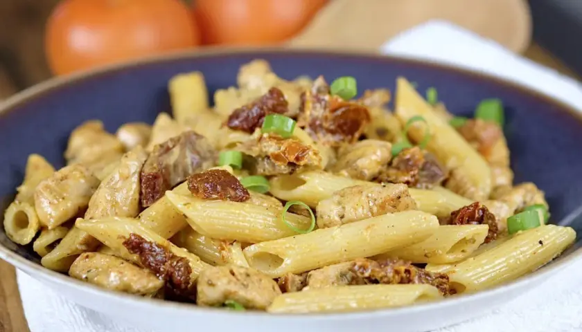 Penne z kurczakiem i suszonymi pomidorami, posypane szczypiorkiem. Pyszne danie, które zachwyci każdego smakosza.