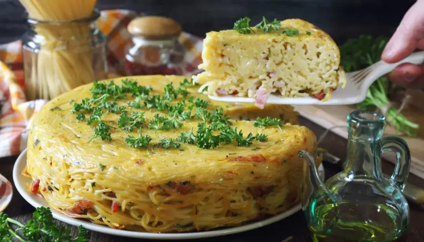Pyszne spaghetti z piekarnika, zapiekane w formie, z kawałkami boczku i posypane natką pietruszki.