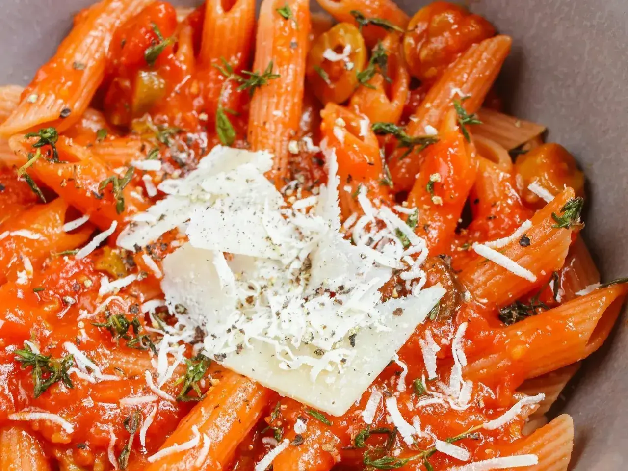 Szybki obiad z makaronem penne w sosie pomidorowym, posypany parmezanem i ziołami. Idealne danie na szybki posiłek.