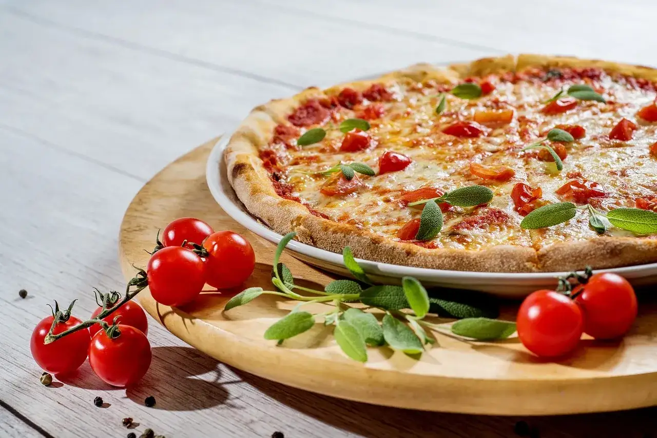 Pyszna pizza z pomidorkami i bazylią, idealna na każdy program kulinarny.