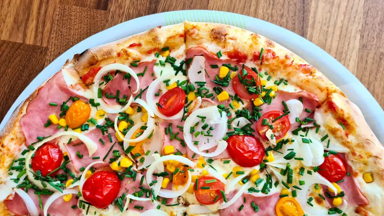 Pyszna pizza 32 cm na ile osób? Ta z szynką, pomidorkami, kukurydzą i cebulą z pewnością zadowoli 2-3 głodomorów.