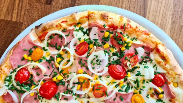 Pyszna pizza 32 cm na ile osób? Ta z szynką, pomidorkami, kukurydzą i cebulą z pewnością zadowoli 2-3 głodomorów.
