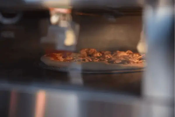 Pizza Dr. Oetker piecze się w piekarniku, apetycznie rumieniąc.
